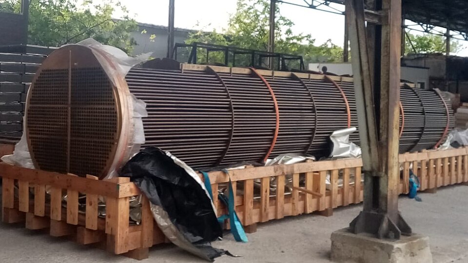 Large cylindrical industrial equipment resting on wooden pallets in a warehouse yard.